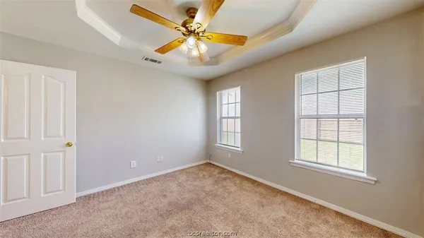an empty room with windows and fan