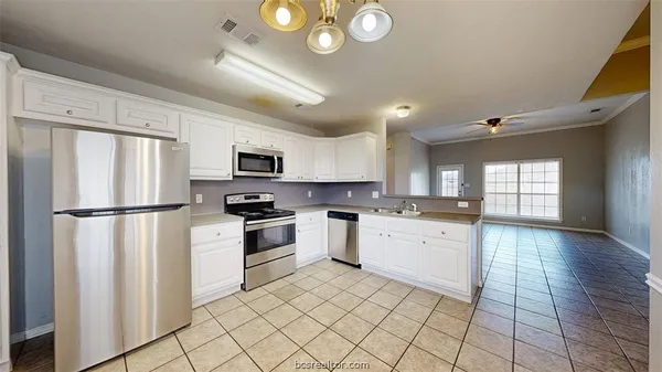 a kitchen with white cabinets and appliances