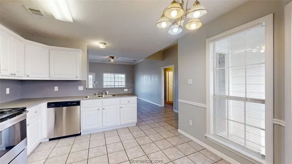 a kitchen with white cabinets and sink