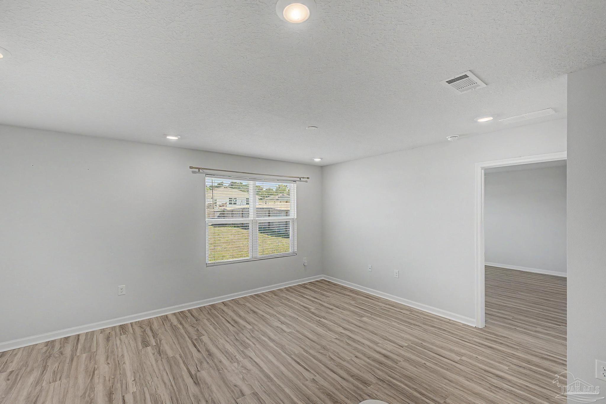 2665 Saltgrass Way Crestview, FL 32536 - Photo 8 of 22 an empty room with wooden floor and windows
