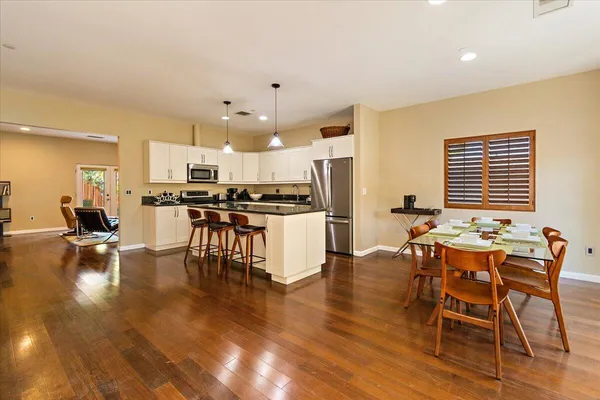 a kitchen with stainless steel appliances a dining table chairs stove a refrigerator and cabinets