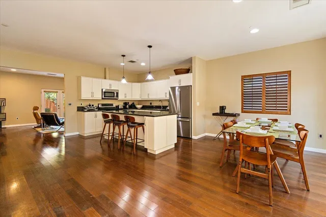 a kitchen with stainless steel appliances a dining table chairs stove a refrigerator and cabinets