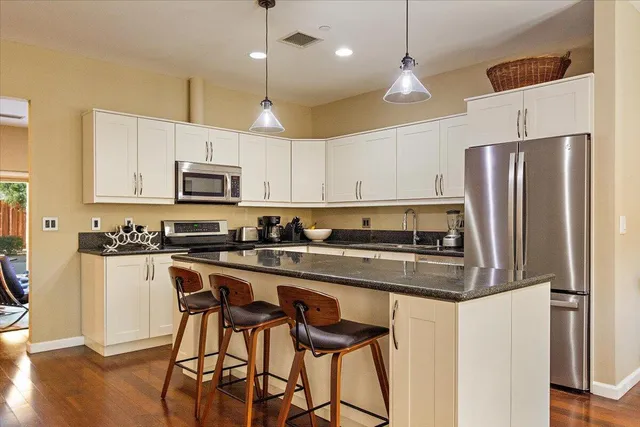 a kitchen with stainless steel appliances a stove a sink a refrigerator a center island and chairs