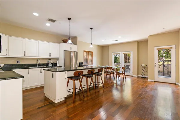 a kitchen with stainless steel appliances granite countertop a stove top oven a dining table and chairs with wooden floor