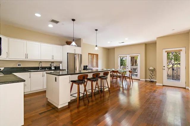 a kitchen with stainless steel appliances granite countertop a stove top oven a dining table and chairs with wooden floor