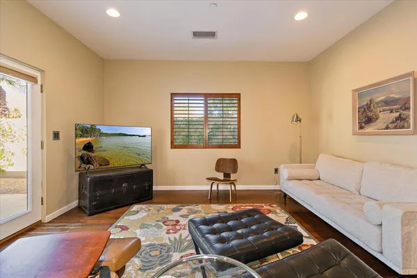 a living room with furniture and a dresser next to a window