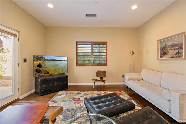 a living room with furniture and a dresser next to a window