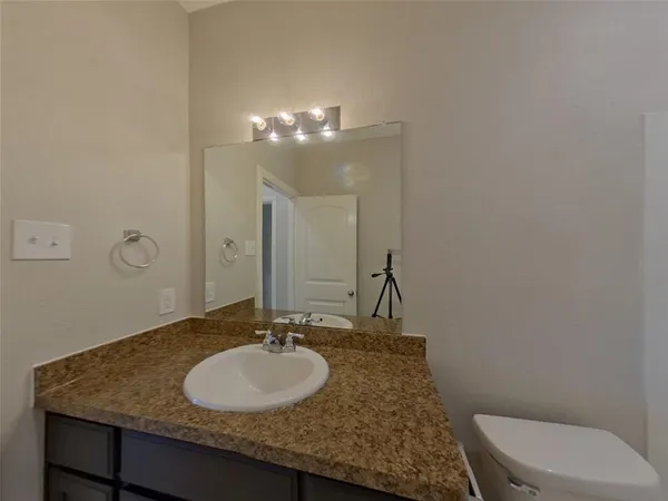 a bathroom with a granite countertop sink a toilet and a mirror