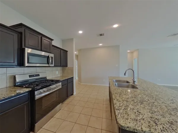 a kitchen with stainless steel appliances granite countertop a sink stove and microwave