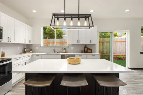 a kitchen with a sink a stove a window cabinets and dining table