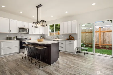 a kitchen with a sink stove and white cabinets with wooden floor