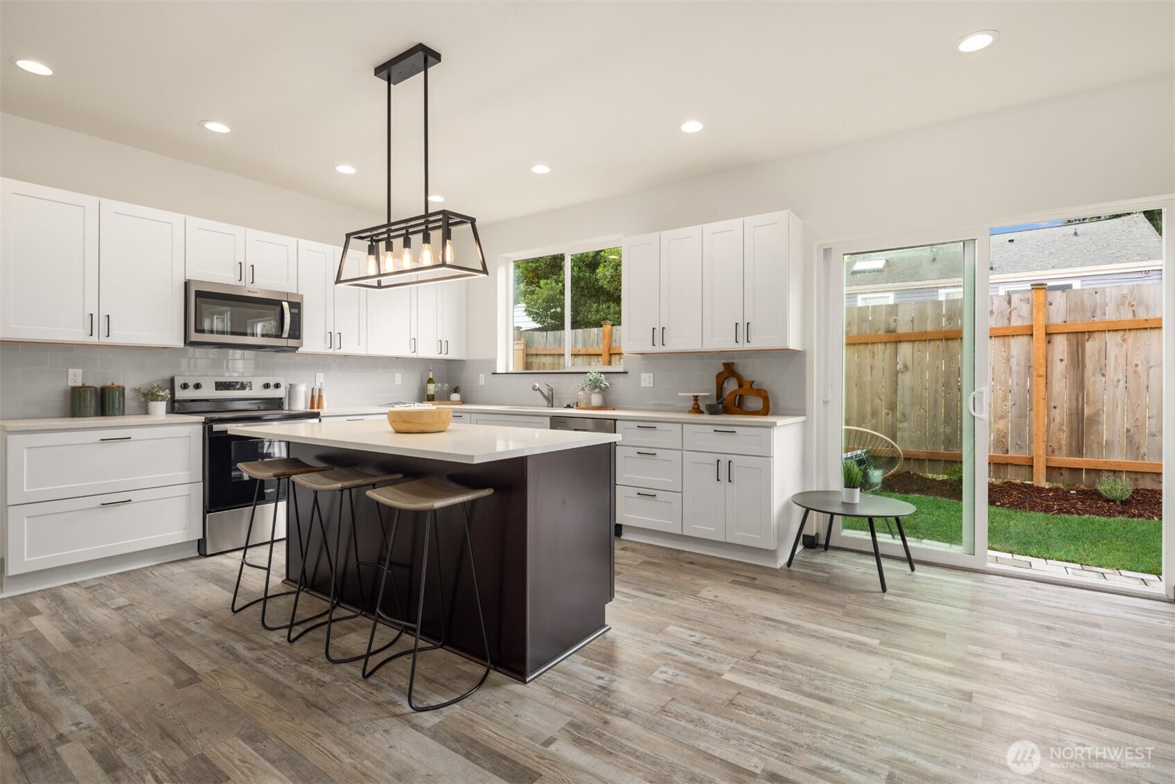 9245 Kelsey Lane Southwest Seattle, WA 98106 - Photo 6 of 33 a kitchen with a sink stove and white cabinets with wooden floor