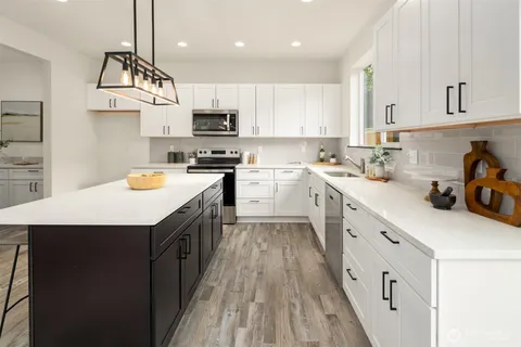 a kitchen with stainless steel appliances a sink a stove top oven a counter space and cabinets