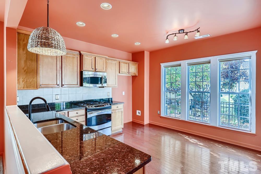 564 Tomkins Loop Cary, NC 27519 - Photo 8 of 28 a kitchen with stainless steel appliances granite countertop a sink a stove and a refrigerator