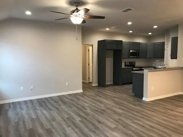 an empty room with wooden floor and stainless steel appliances