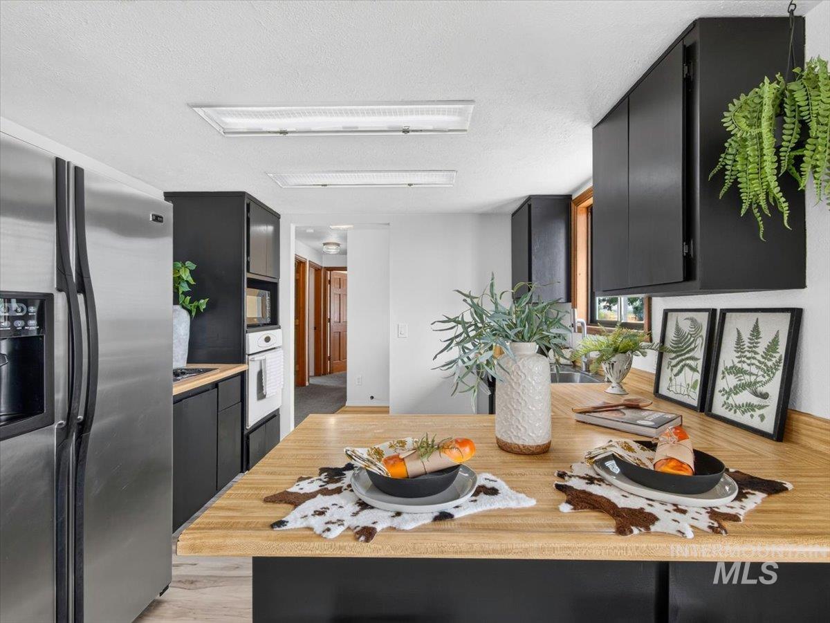 8989 Hillview Road Emmett, ID 83617 - Photo 17 of 50 Kitchen featuring dark cabinetry, stainless steel refrigerator, built-in oven, and wood-finish countertops