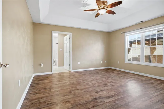 a view of an empty room with a window and wooden floor