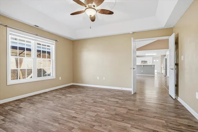 an empty room with wooden floor and a ceiling fan
