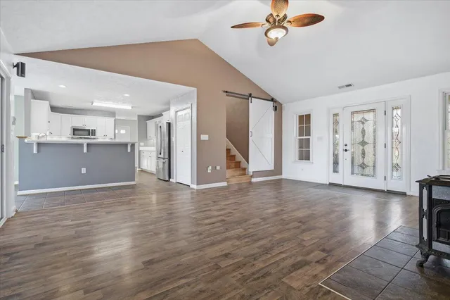 a view of an empty room with wooden floor and stairs
