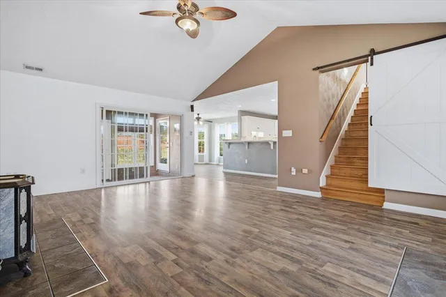 a view of an empty room with a window and a kitchen