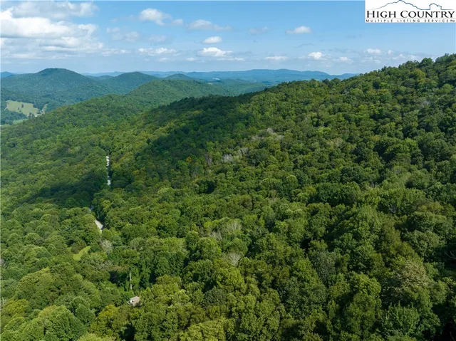 an aerial view of residential house with outdoor space and trees all around