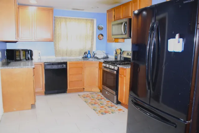a kitchen with stainless steel appliances granite countertop a refrigerator and a stove