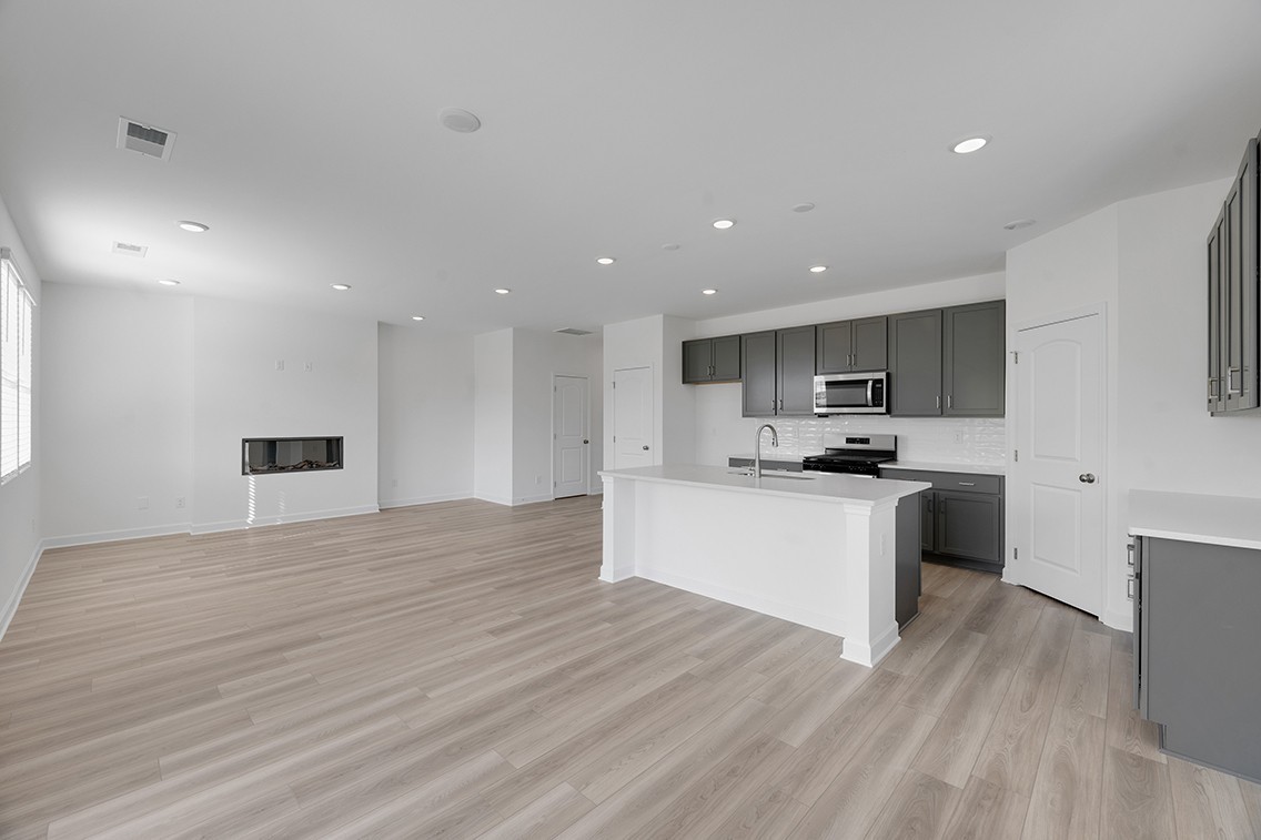 199 East Millbrook Drive Spring Hill, TN 37174 - Photo 9 of 32 a large white kitchen with kitchen island a sink dishwasher a stove a refrigerator and white cabinets with wooden floor