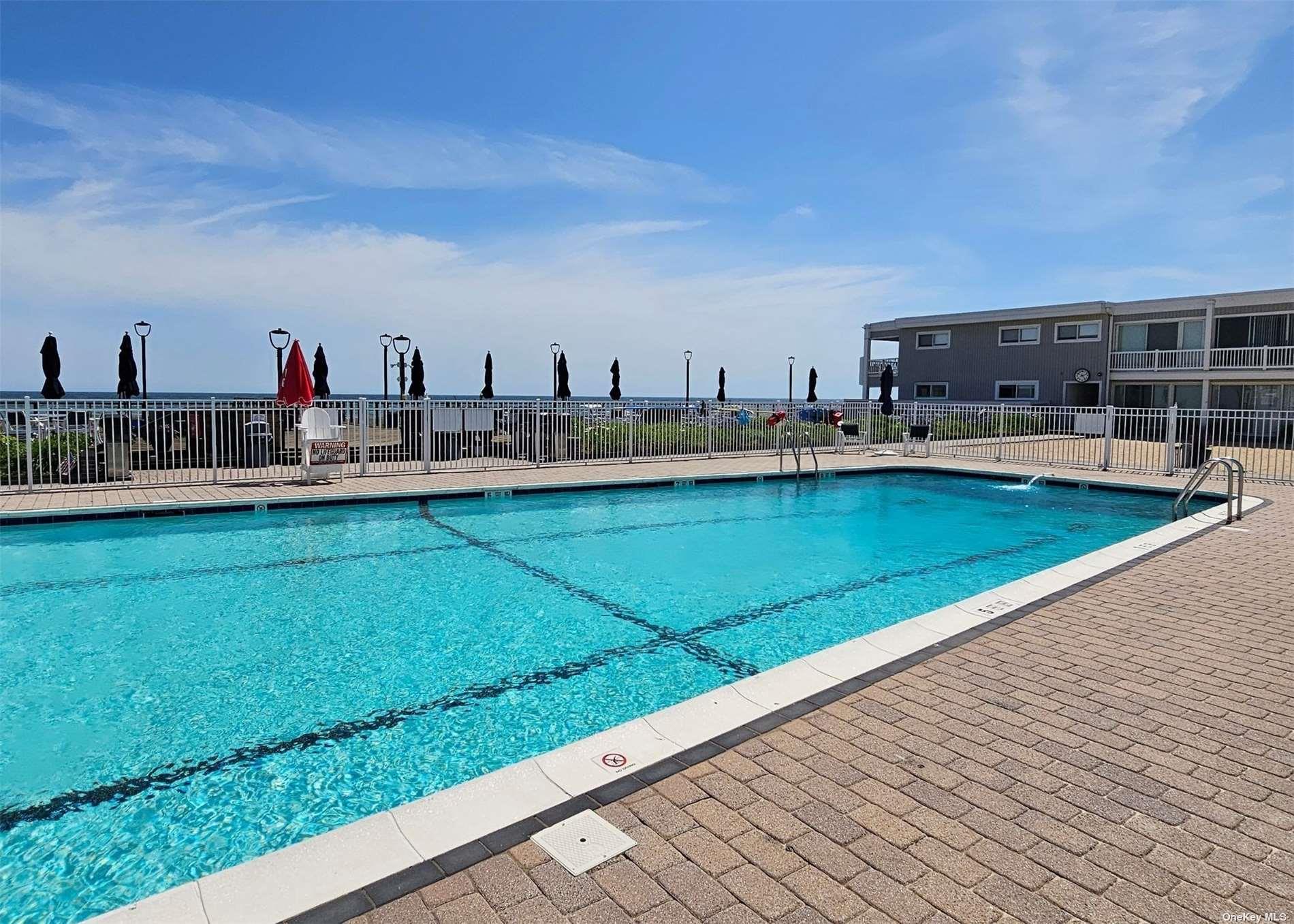 585 Dune Road, Unit L9 Westhampton, NY 11978 - Photo 9 of 20 a view of a swimming pool with a lawn chairs and a yard