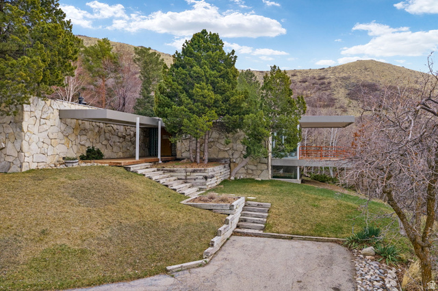 Stone-clad exterior featuring a covered entry, wood decking, and tiered landscaping