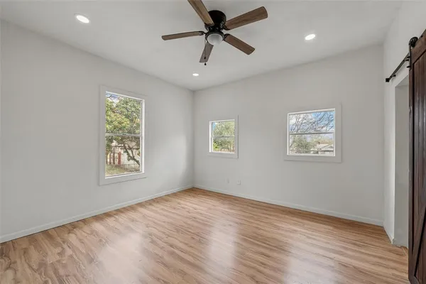 a view of an empty room with a window and wooden floor