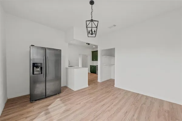 a view of a kitchen with wooden floor and a refrigerator