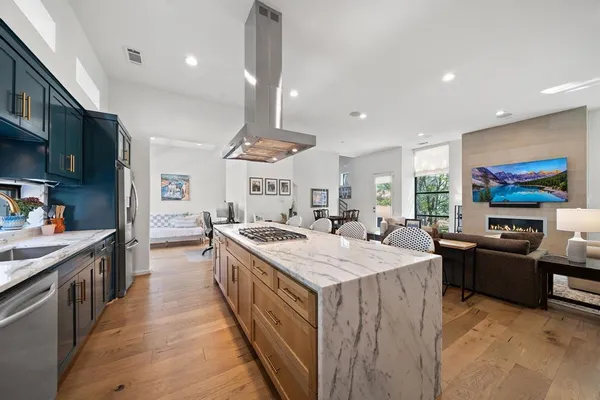 a large kitchen with stainless steel appliances a stove a sink dishwasher and a flat screen tv