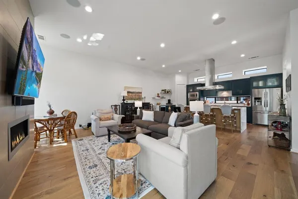 a kitchen with stainless steel appliances granite countertop a refrigerator a stove a sink a dining table and chairs with wooden floor