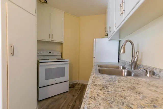 a kitchen with granite countertop white cabinets and a sink