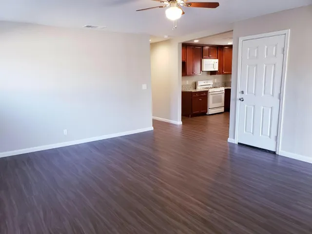 an empty room with wooden floor cabinet and a view of bathroom