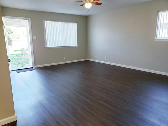 an empty room with wooden floor and windows
