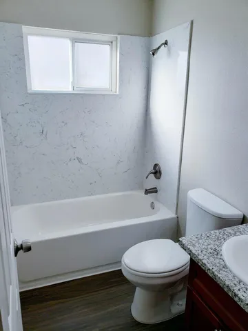 a bathroom with a granite countertop toilet a sink and bathtub