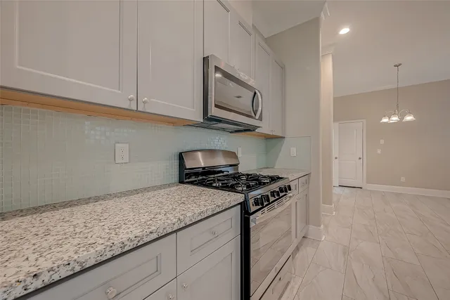 a kitchen with granite countertop stainless steel appliances a stove top oven and cabinets