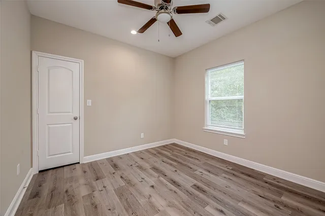 a view of empty room with wooden floor and ceiling fan