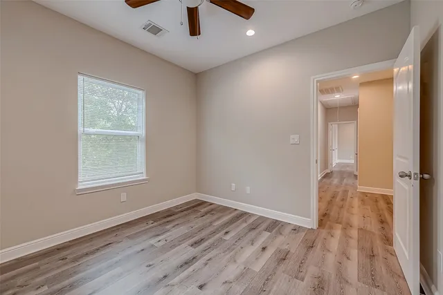 an empty room with wooden floor cabinet and windows