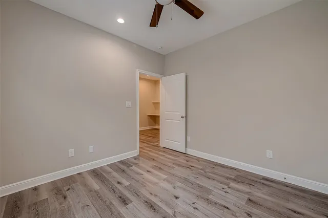 an empty room with ceiling fan and wooden floor