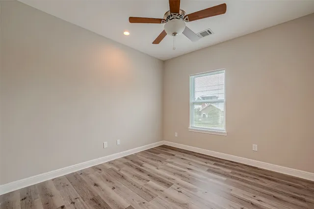 an empty room with a window and a ceiling fan