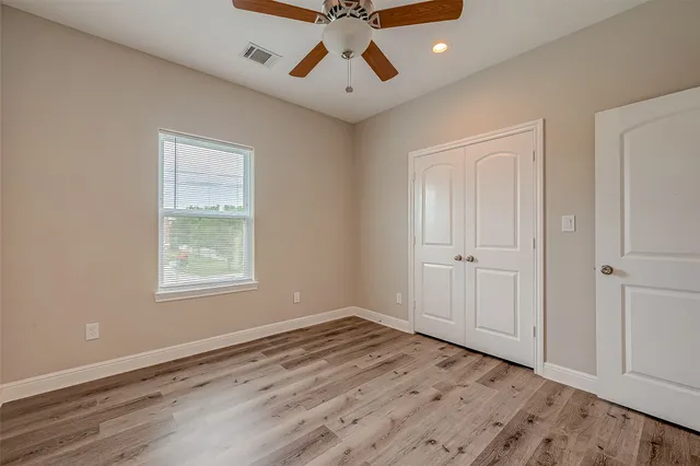 a view of an empty room with window and wooden floor