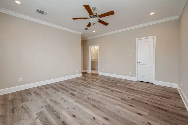 an empty room with wooden floor and ceiling fan