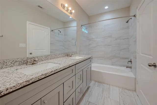 a bathroom with a granite countertop sink a mirror and a bathtub