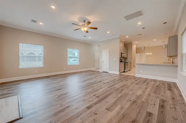 a view of an empty room with a window and wooden floor