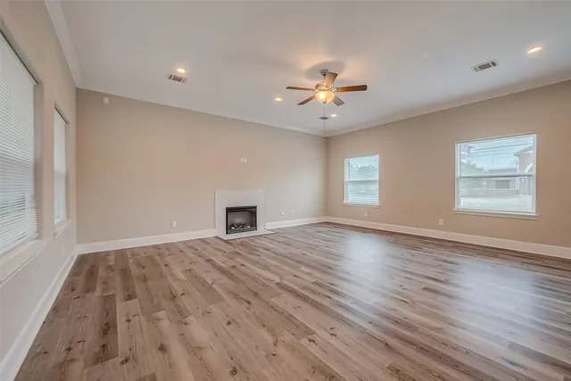 a view of an empty room with a window and wooden floor