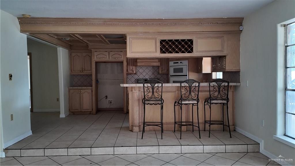 612 West Ramirez Street Rio Grande City, TX 78582 - Photo 15 of 40 Kitchen featuring tasteful backsplash, light tile patterned flooring, a peninsula, a breakfast bar, and multiple ovens