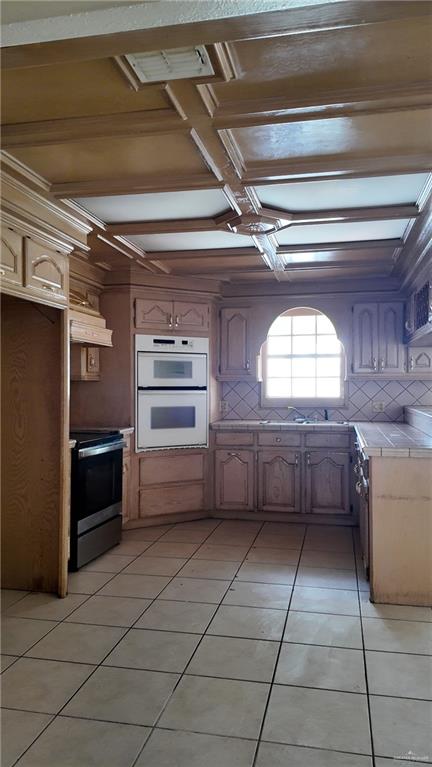 612 West Ramirez Street Rio Grande City, TX 78582 - Photo 16 of 40 Kitchen with electric range, tile counters, decorative backsplash, white double oven, and light tile patterned flooring