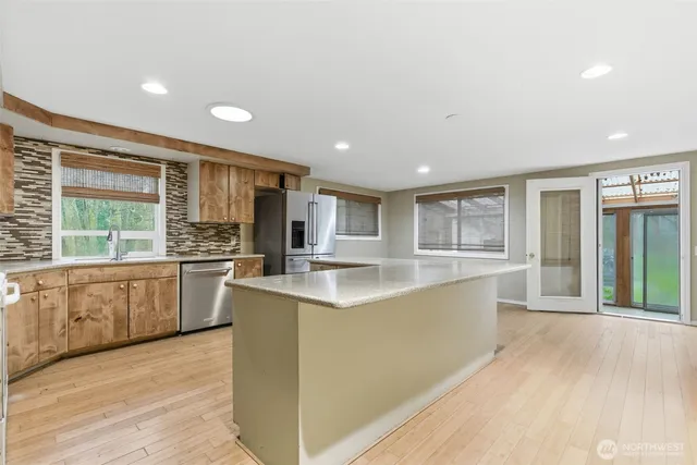 a large kitchen with kitchen island a large window a sink and cabinets